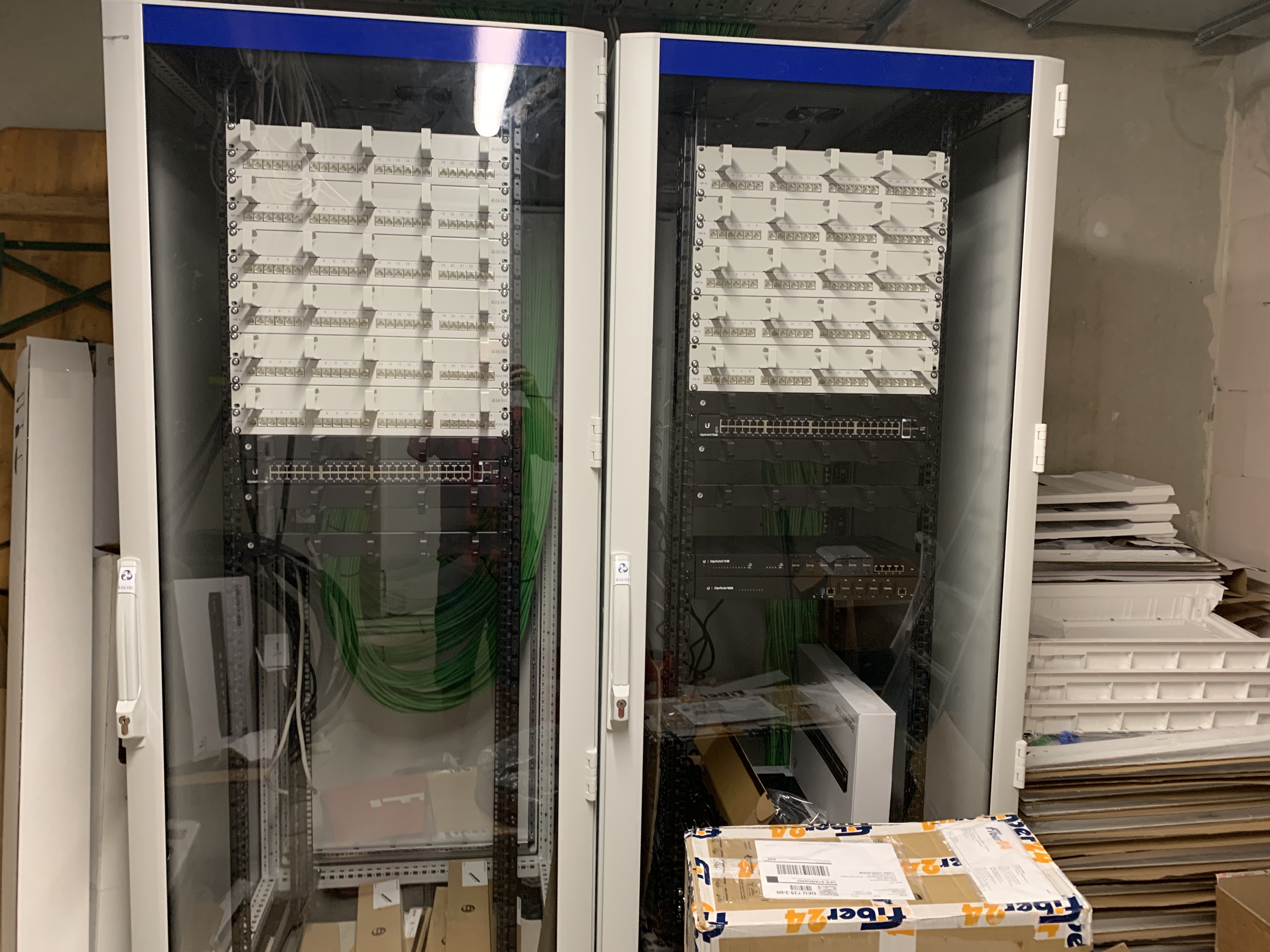 Zwei weiße Netzwerkschränke mit strukturierten grünen Patch-Kabeln, Neuinstallation